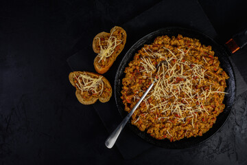 lentil stew with spicy herbs and tomatoes in a frying pan with thorn cheese on a stone cutting board. national Jewish cuisine concept. top view with copy space for creative food mackup