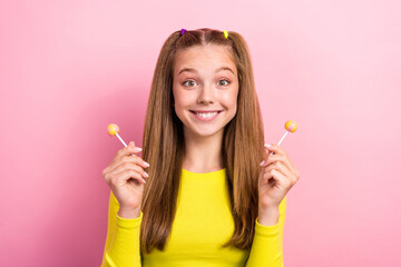 Photo of cheerful pretty cute lady wear yellow trendy outfit arm hold candies sugary sweets addiction isolated on pink color background