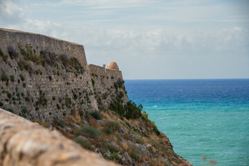 Fototapeta na wymiar The wall of the Fortezza fortress ruins in Rethymno and the sea
