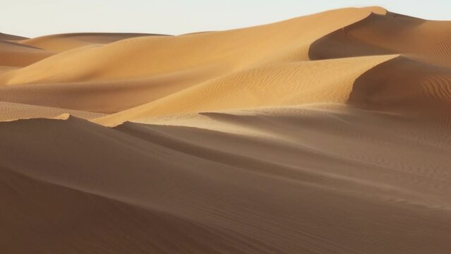 Sand blowing over sand dunes in wind, Sahara desert, zoom out