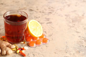 Glass cup of tea, lemon and pills on grunge background, closeup