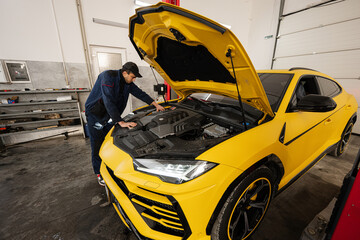 Mechanic open hood of yellow sport car suv.