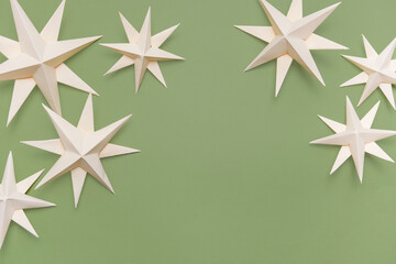 Merry Christmas.Christmas stars handmade light beige green background.Monochrome,Christmas background,holiday card.DIY christmas flat lay copy space.Christmas zero waste, paper, eco postcard