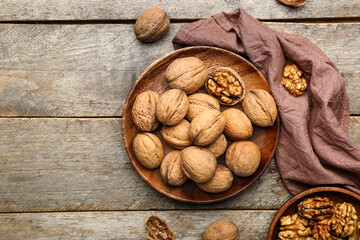 Plate of fresh walnuts on wooden background