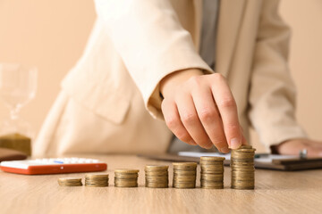 Woman with stacks of coins at wooden table, closeup. Budget concept