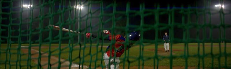 Portrait of Caucasian kid boy baseball player practicing hits on a rainy evening. Shot with...
