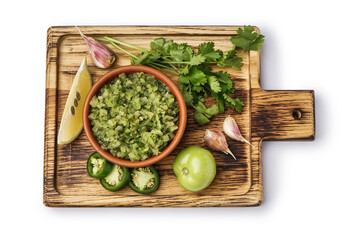 Wooden board with bowl of green salsa sauce and ingredients on white background - obrazy, fototapety, plakaty