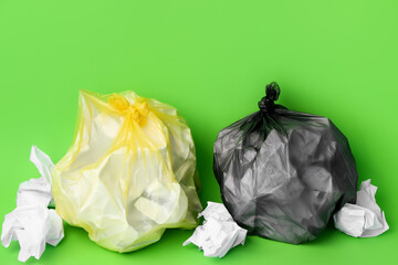 Garbage bags with crumpled paper on green background