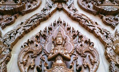 Low angle view of wood carving deva clasping hand pattern on teak wooden wall of Wat Krok Krak temple at Samut Sakhon, Thailand - obrazy, fototapety, plakaty