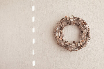 Christmas wreath on white wall. Natural materials. Eco decorations, ornaments, hand made decor. Winter and New Year holidays.