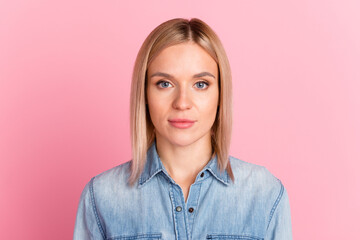 Headshot of serious young female wearing shirt looking at camera standing isolated at pastel studio...