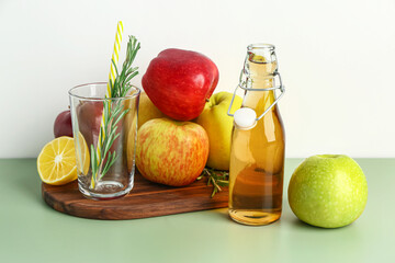 Wooden board with ripe apples and glass of fresh juice on color table