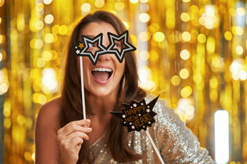 Young woman over gold background with photo booth accessories