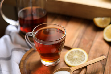 Glass cup with delicious tea, lemon and sugar on table, closeup. Space for text