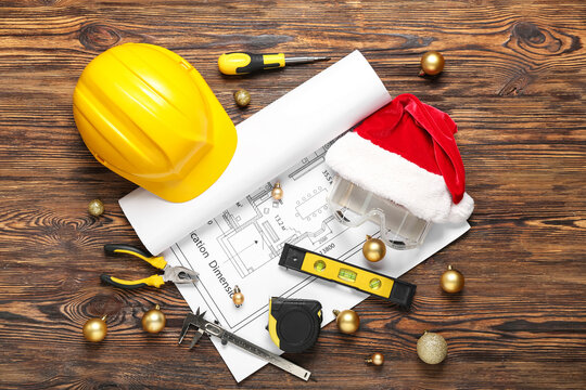 Builder's tools with Santa hat and Christmas balls on wooden background