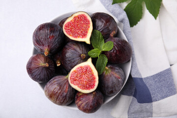 Bowl of tasty ripe figs on light table, top view