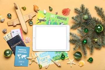 Tablet computer with travel accessories, Christmas branches and balls on beige background