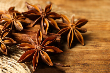 Aromatic anise stars and cinnamon sticks on wooden table, closeup