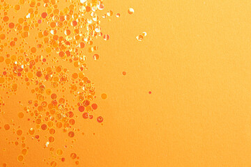 Shiny bright glitter on orange background, flat lay. Space for text