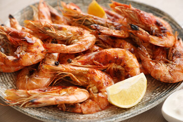 Delicious cooked shrimps served with lemon on plate, closeup