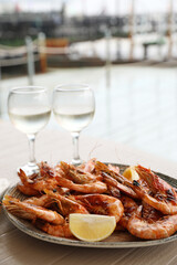 Plate of delicious cooked shrimps served with lemon and wine at table outdoors
