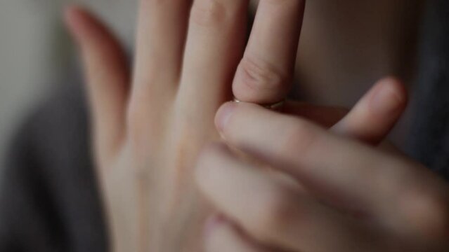 Wedding ring stuck on finger, woman cant take off ring hands close up. A woman is taking off her wedding ring