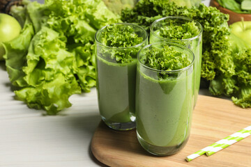 Green smoothie of lettuce leaves in glasses on white wooden table