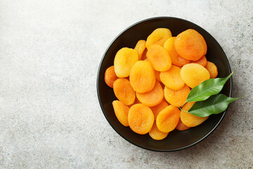 Plate of tasty apricots and space for text on grey table, top view. Dried fruits