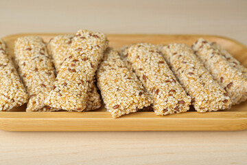 Plate with tasty sesame seed bars on wooden table, closeup