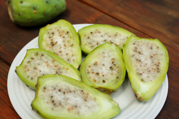 Tasty prickly pear fruits on wooden table, closeup