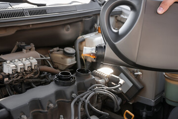 Man pouring motor oil into car engine, closeup