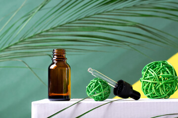 Dropper bottle with pipette on podium against the green background. Spa concept. Manufacturing beauty products 