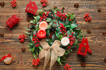 Stylish Christmas wreath with burning candles and decorations on wooden background