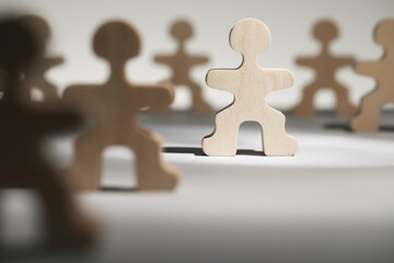 Recruitment and hiring concept. Human wooden figure in beam of light among others on table