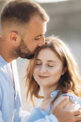 Fototapeta premium Portrait of a lovely couple standing together on the greenfield. Happy couple expecting a baby, young family concept