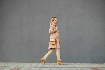 A fashionable middle-aged woman is walking on the street downtown.