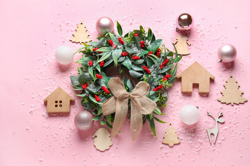 Composition with beautiful Christmas wreath, decorations and snow on pink background