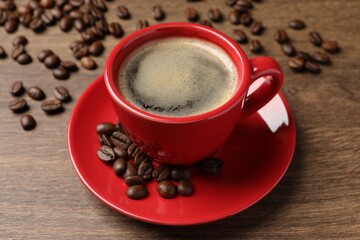 Cup of aromatic coffee and beans on wooden table