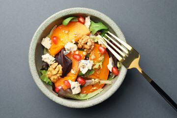Delicious persimmon salad with cheese and pomegranate on grey table, top view