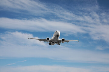 Modern white airplane flying in cloudy sky