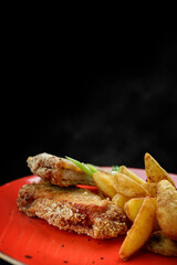 Pork schnitzel with potatoes, sauce and herbs, vertical