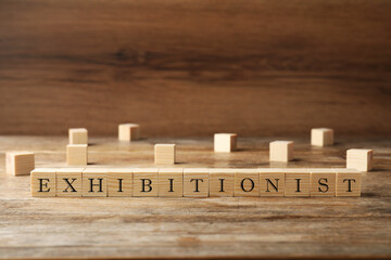 Word EXHIBITIONIST made with wooden cubes on table