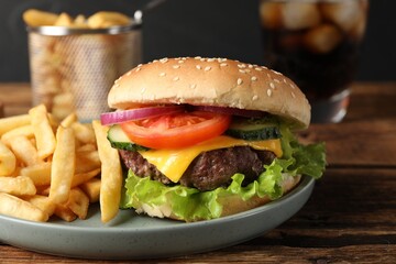 Delicious burger, soda drink and french fries served on wooden table, closeup