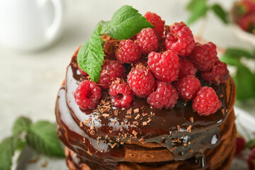 Chocolate Pancakes. Pancakes with fresh raspberry with chocolate glaze or toppings in gray bowl on light gray table background. Homemade classic american pancakes. Page for magazine concept.