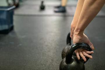 Low section of man lifting kettlebell in gym