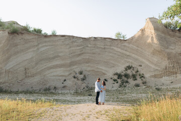 Portrait of a lovely couple standing together on the greenfield. Happy couple expecting a baby, young family concept