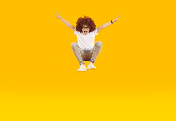 Funny crazy preteen boy having fun jumping high and hovering on orange background in studio. Child...