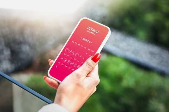 Menstruation calendar. Woman tracking periods by using menstrual calendar app on phone