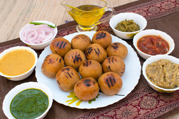 Litti in white plate with tomato, brinjal, potato, pointed gaurd and coriander chutney or chokha...