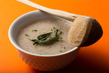 traditional Moroccan Cream of Barley Soup or belboula with a wooden spoon on the orange background